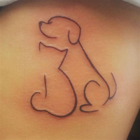 a dog tattoo on the back of a woman's shoulder, with an outline of a dog