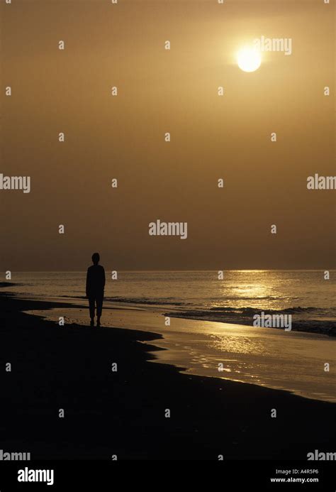 man walking alone on a beach Stock Photo - Alamy