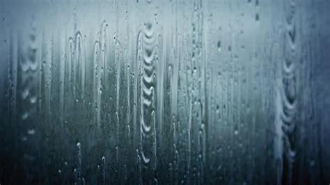 rain drops on the window glass in front of a dark blue background with ...