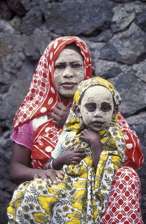 two women with face paint on their faces sitting next to each other in front of a stone wall