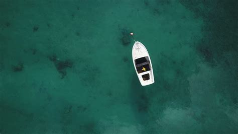 Drone shot of wooden rowing boat in pristine crystal clear blue water ...