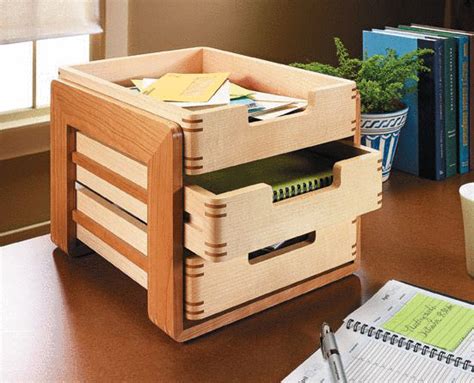 a wooden box with two drawers on top of a desk next to a notebook and pen