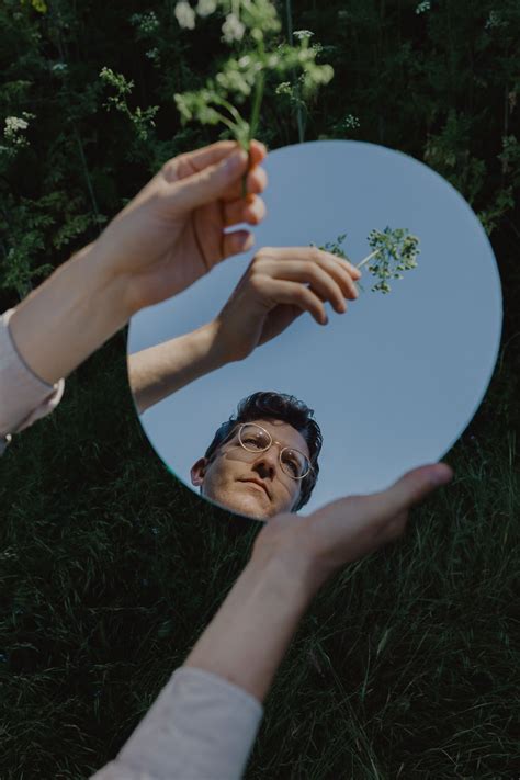 two people reaching out their hands to touch a plate with flowers on it in the grass