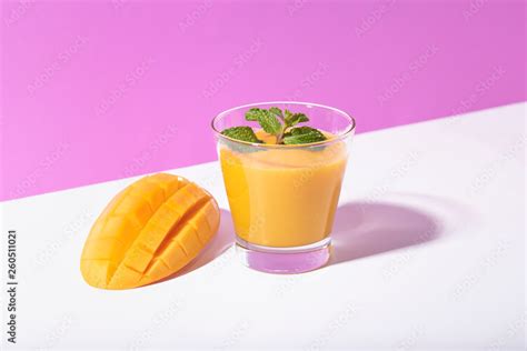 Fresh mango smoothie and ripe mango slice on purple background. summer ...