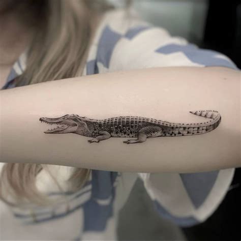 Micro-realistic crocodile tattoo on the forearm.