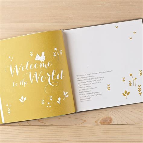 an open book with the words welcome to the world written on it and gold foil