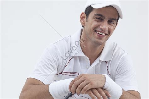 Portrait Of A Male Tennis Player With A Racket Smiling Isolated On Gray ...