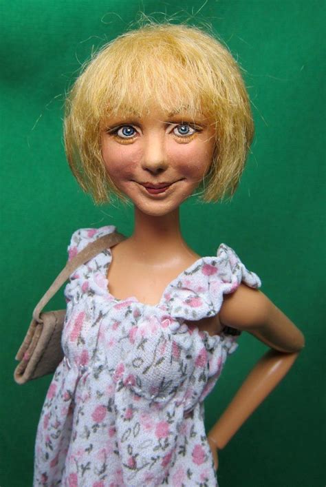 a doll with blonde hair and blue eyes wearing a pink floral dress on a green background