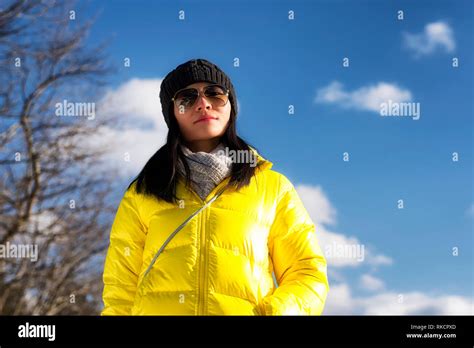 A Chinese woman wearing a yellow winter jacket looking at the camera on a cold winter day in ...