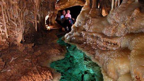 some people are standing in a cave with green water