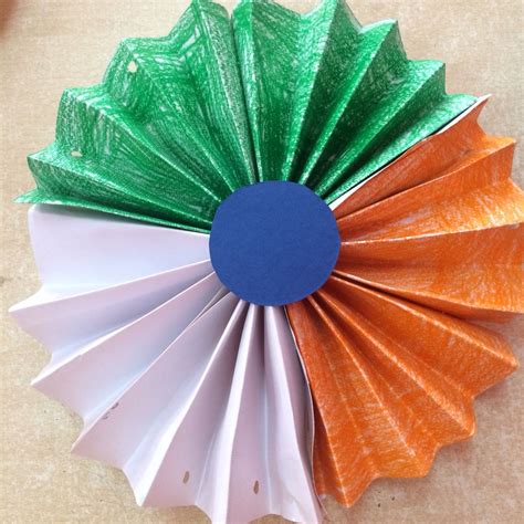 an orange, green and white paper flower on a table