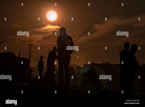 Sunset silhouette of holding fish Stock Photo - Alamy