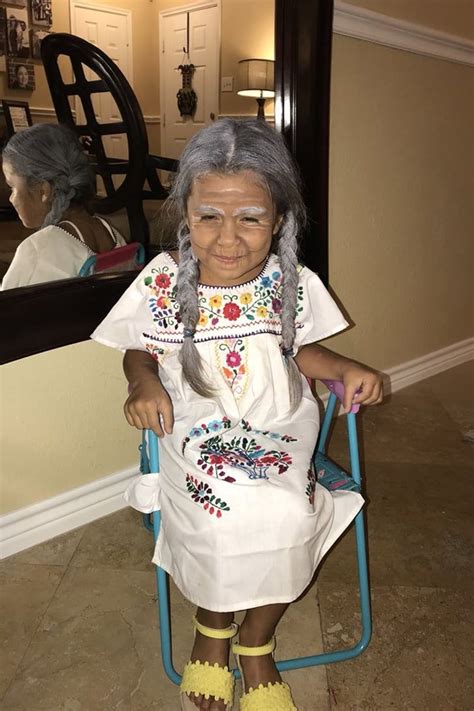 an old woman sitting on a chair in front of a mirror