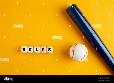 Wooden baseball bat and a ball on yellow background with the word rules. Baseball rules concept ...