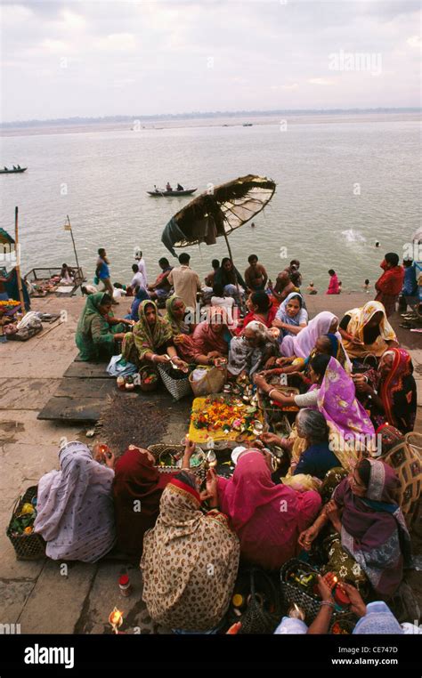 women praying on the steps of the bathing ghat on ganges river ganga ...