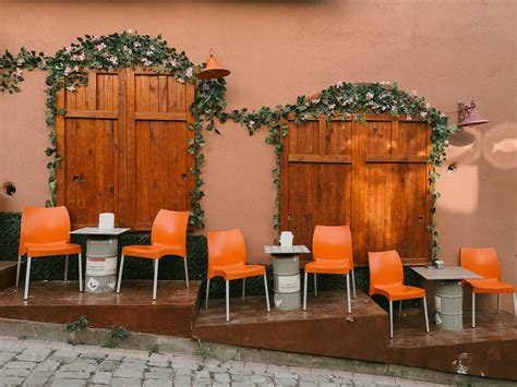 Seats of Sidewalk Cafe on Steps against Wooden Two-winged Door · Free Stock Photo