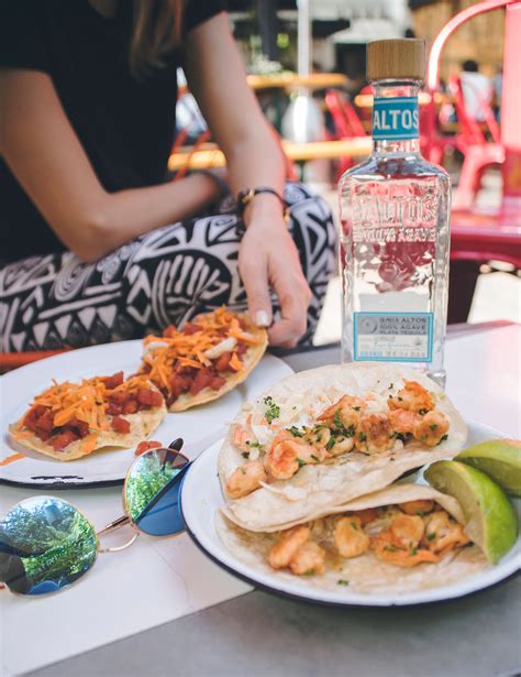 a plate with tacos and a bottle of alcohol on the table next to it