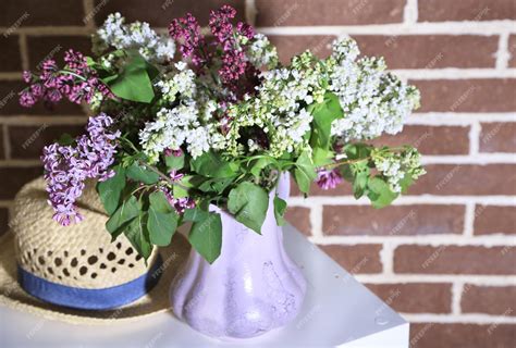 Premium Photo | Beautiful lilac flowers in vase on stand on color wall background