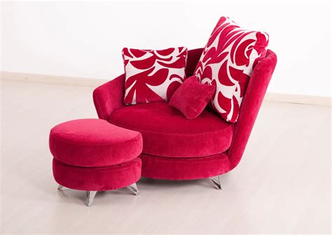 a red chair and ottoman with two pillows on it in a white living room area