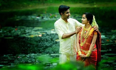 a man and woman standing next to each other near water lilies in a pond