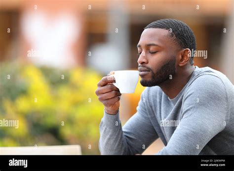 Man with black skin enjoying aroma of coffee cup in a restaurant terrace Stock Photo - Alamy