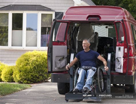 Man with spinal cord injury in a wheelchair getting in his accessible van — sitting, open ...