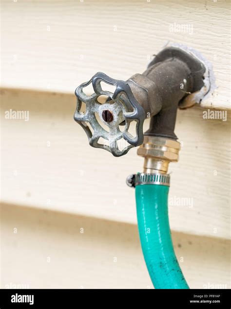 A water spigot connected to the exterior of a house, with a hose connected. USA Stock Photo - Alamy