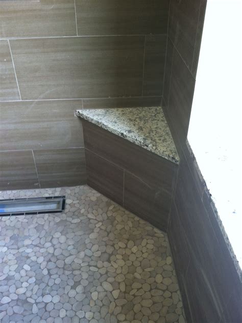 Walk in Shower with pebble floors, solid surface corner bench and tile detailing at drain ...