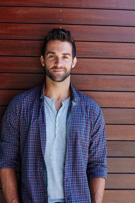 Hes an Easy Going Guy. Portrait of a Handsome Man Standing Against a Wooden Wall. Stock Photo ...