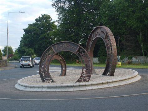 a sculpture in the middle of a roundabout with cars driving by it and ...