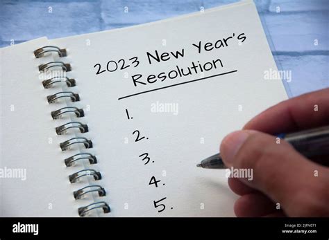 2023 New Year's Resolutions text on note pad with hand holding a pen ...