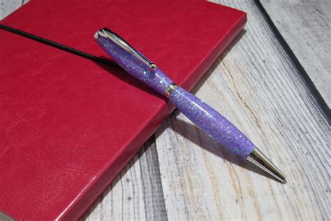 a purple pen sitting on top of a red book