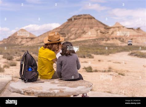 Back view of unrecognizable mother and daughter exploring map together while hiking in Bardenas ...