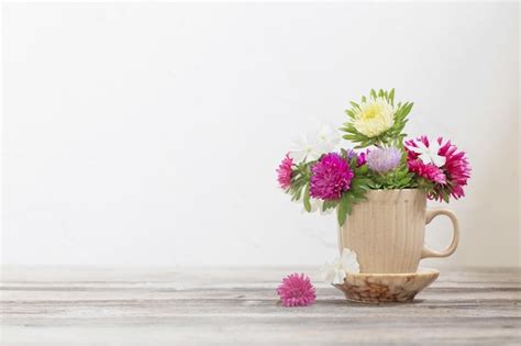 Premium Photo | Beautiful flowers in cup on wooden table on background ...