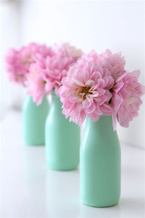 three green vases with pink flowers in them
