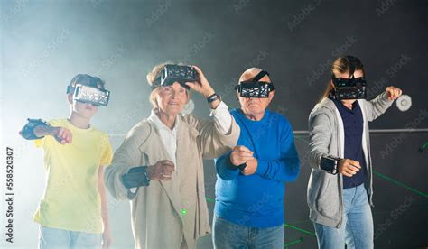 Family of four people, grandparents and grandchildren, playing VR games together. Stock Photo ...