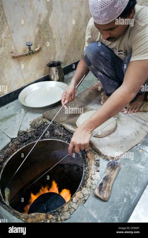 L M Rahman preparing and cooking fresh naan bread in the tandoor oven ...