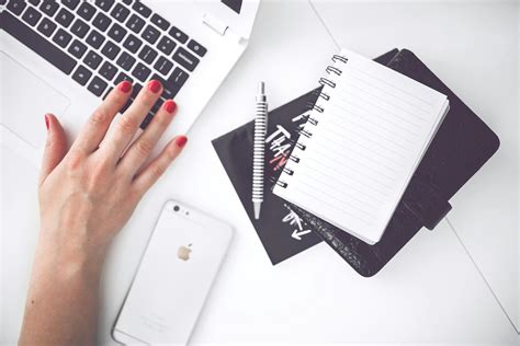 White laptop, female hand, note, pen, phone, desk · Free Stock Photo
