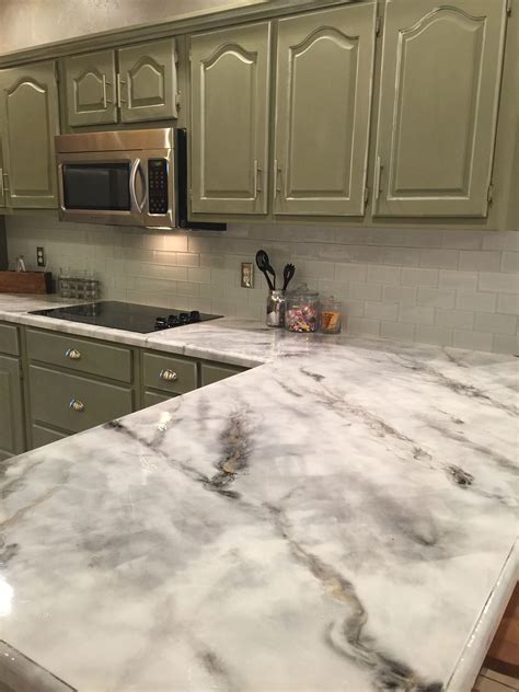 a kitchen with green cabinets and white marble counter tops, along with ...