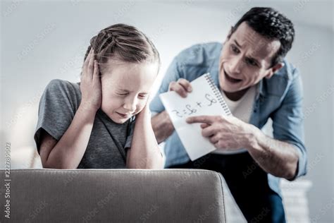Violent parent. Inadequate angry father screaming on the daughter while checking her homework ...