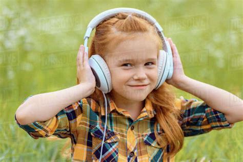 portrait of smiling kid listening music in headphones with green grass on background - Stock ...