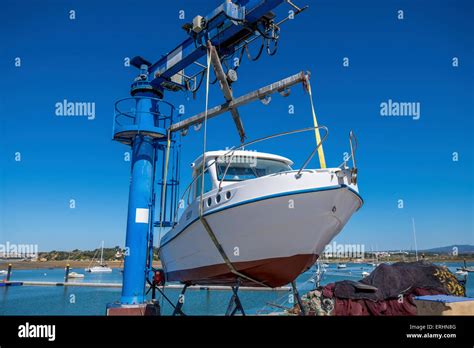 Small motor boat being lifted out of the water with a boat lift on the quayside ready for ...