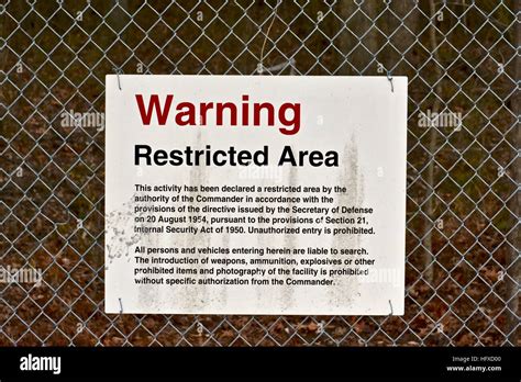 A restricted area sign on the outside of a US Army installation fence ...