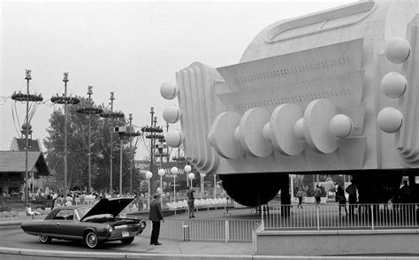 a black and white photo of a car parked in front of a large structure with balls on it