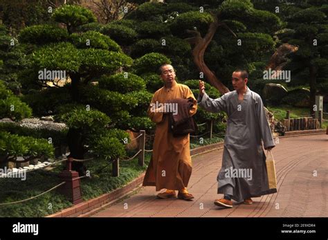 HONG KONG - 22th FEBRUARY, 2015: Monks walking in green oriental garden ...