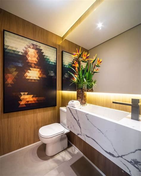 a bathroom with a white toilet sitting next to a sink and a painting on the wall