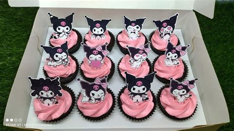 a box filled with lots of pink cupcakes covered in frosting and cats