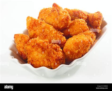 Golden crisp fried crumbed chicken nuggets served in a fluted dish as ...