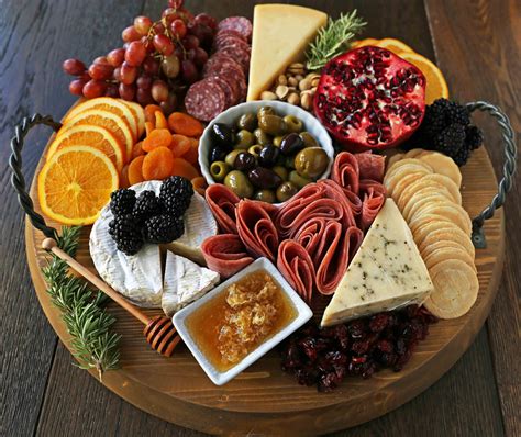 an assortment of cheeses, meats, and fruit arranged on a platter