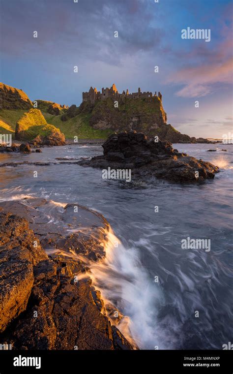 Coastal sunset beneath Dunluce Castle, County Antrim, Northern Ireland ...